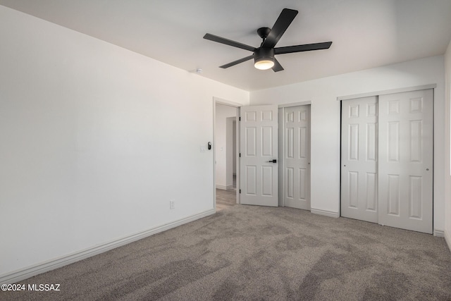 unfurnished bedroom featuring ceiling fan, light colored carpet, and two closets