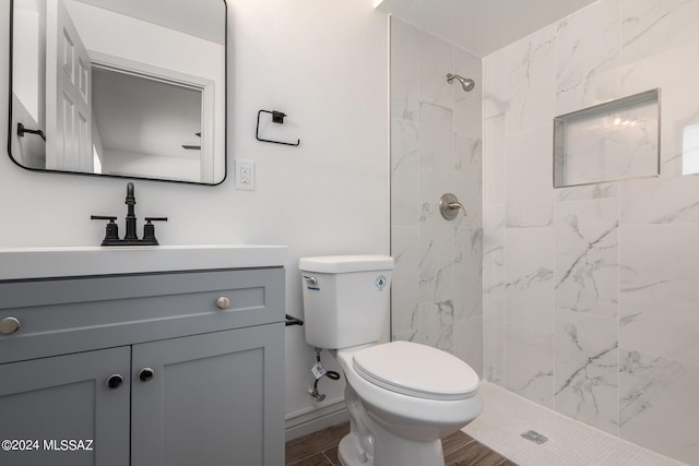 bathroom with toilet, wood-type flooring, vanity, and a tile shower