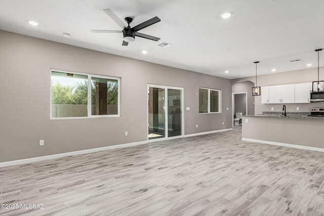 unfurnished living room featuring ceiling fan, sink, and light hardwood / wood-style flooring