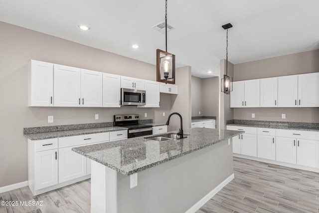 kitchen with stainless steel appliances, decorative light fixtures, sink, and white cabinets