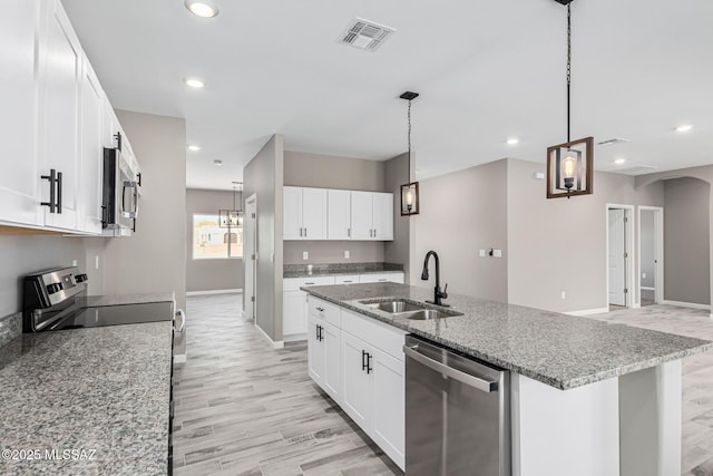 kitchen featuring appliances with stainless steel finishes, sink, a center island with sink, and white cabinets