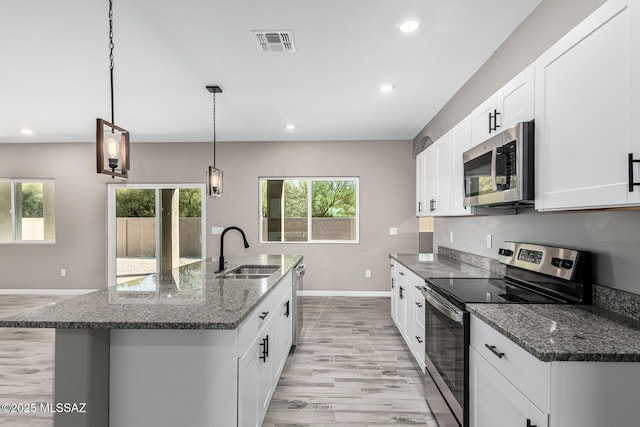 kitchen featuring dark stone countertops, appliances with stainless steel finishes, sink, and pendant lighting