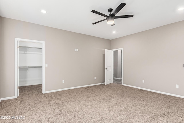 unfurnished bedroom featuring a walk in closet, carpet flooring, ceiling fan, and a closet