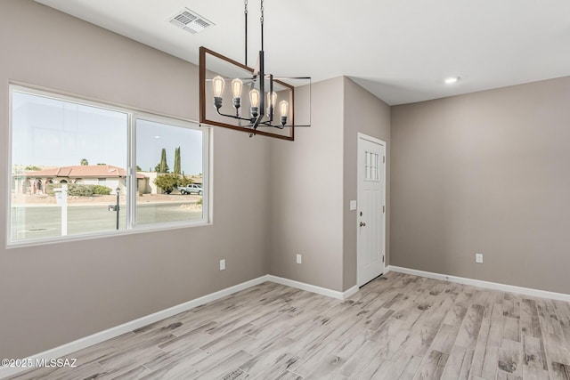 unfurnished dining area featuring light hardwood / wood-style floors and a notable chandelier