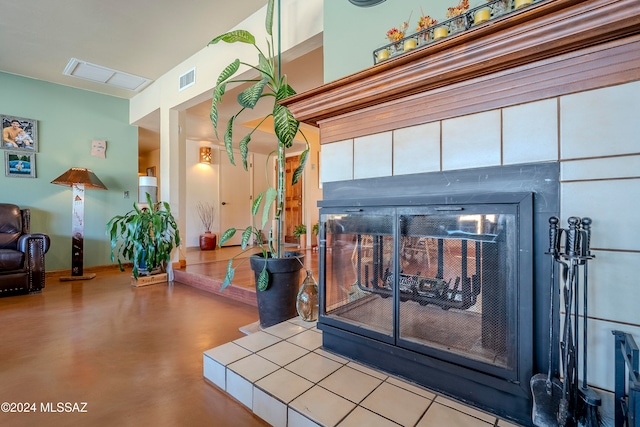 details with concrete flooring and a tiled fireplace