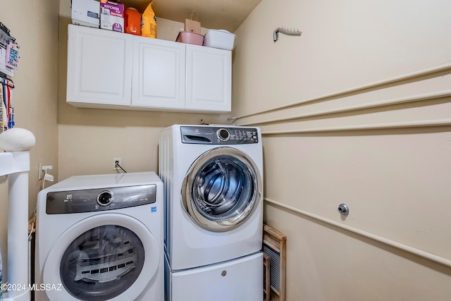 washroom with cabinets and washing machine and dryer