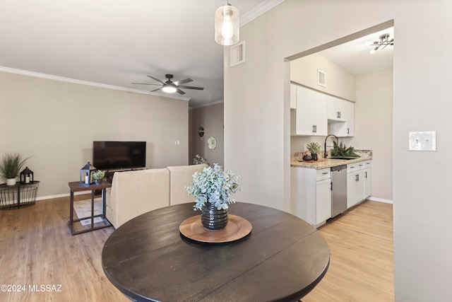 dining area featuring crown molding, sink, and light hardwood / wood-style floors