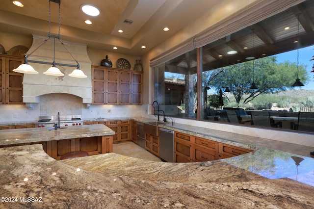 kitchen featuring sink, hanging light fixtures, light stone counters, stainless steel dishwasher, and decorative backsplash