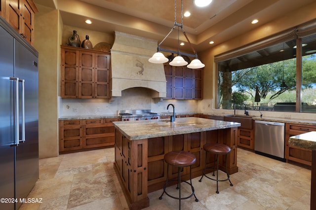 kitchen featuring tasteful backsplash, stainless steel appliances, a kitchen island with sink, sink, and pendant lighting