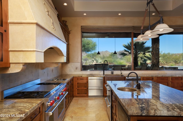 kitchen with high end stove, sink, dark stone counters, and custom exhaust hood