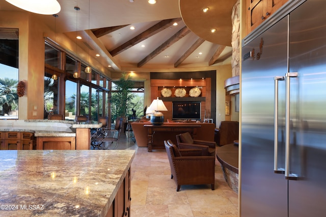 kitchen with beam ceiling, light stone countertops, stainless steel built in fridge, and high vaulted ceiling