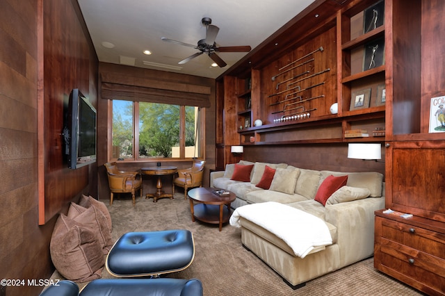 carpeted living room with wooden walls and ceiling fan