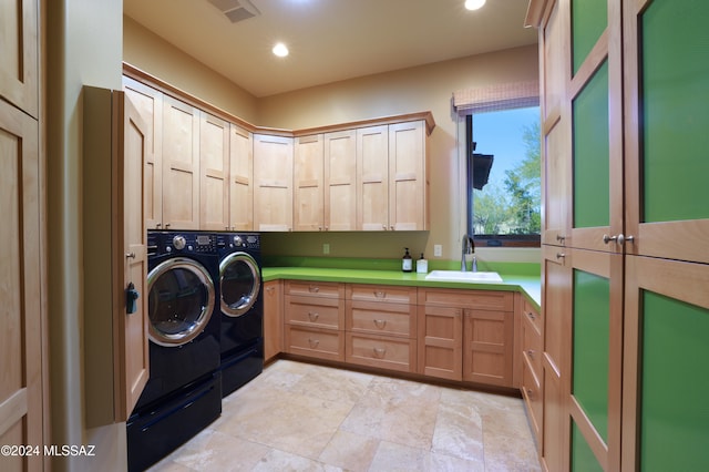 clothes washing area featuring washer and clothes dryer, sink, and cabinets