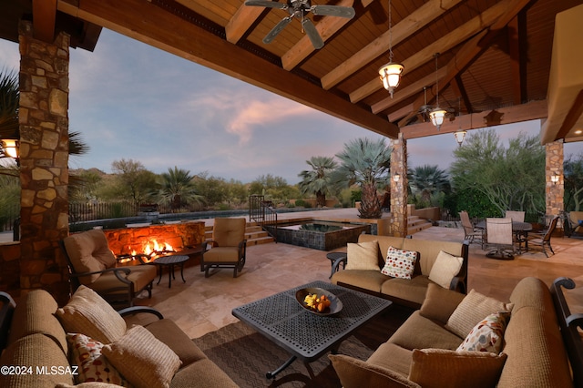 patio terrace at dusk featuring a gazebo, an outdoor living space with a fire pit, and a swimming pool with hot tub