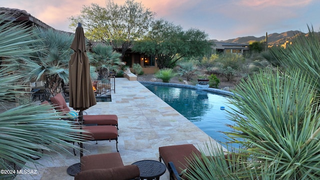 pool at dusk with a mountain view and a patio