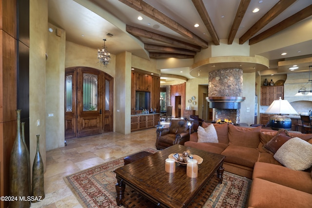 living room with beam ceiling, a fireplace, and a notable chandelier