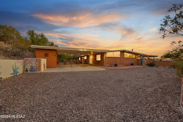 back house at dusk featuring a carport