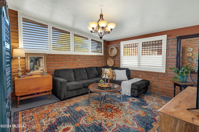 living room featuring a chandelier and brick wall