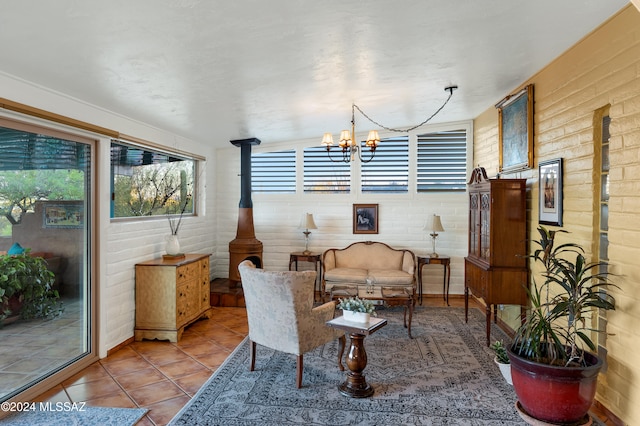 living area featuring light tile patterned floors, an inviting chandelier, a wood stove, and brick wall