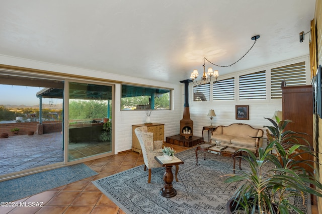 living room with a wood stove, light tile patterned floors, and an inviting chandelier