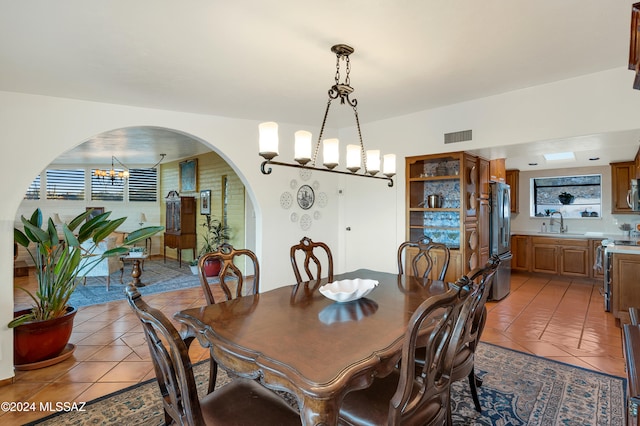 tiled dining room with a chandelier and sink