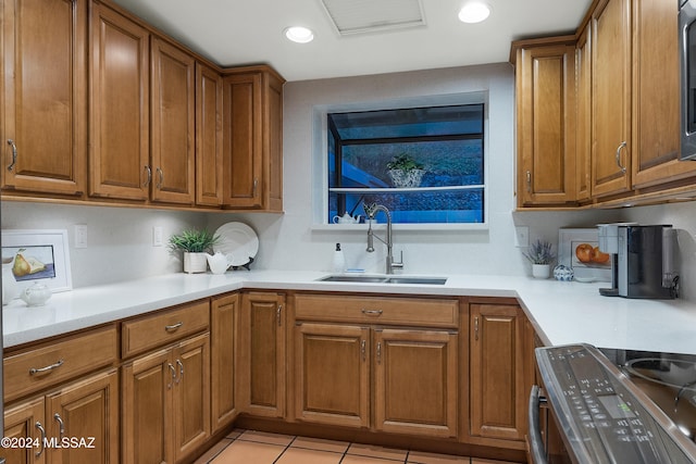 kitchen featuring light tile patterned floors, sink, and stainless steel range oven