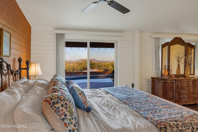 bedroom with access to outside, ceiling fan, and brick wall