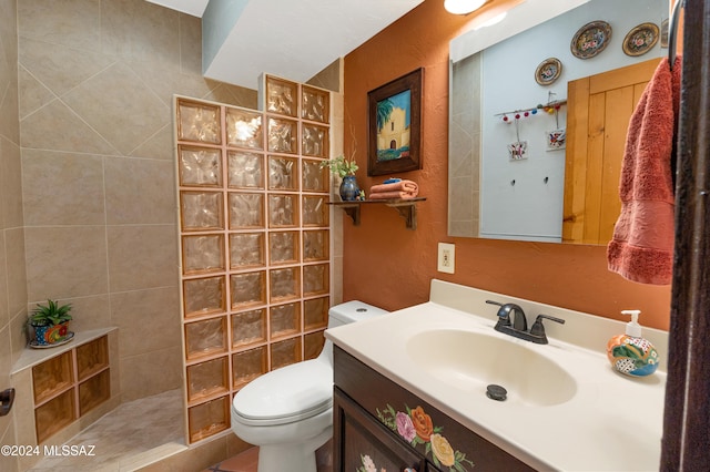 bathroom with tile patterned floors, vanity, toilet, and a tile shower