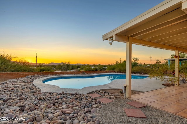 pool at dusk with a patio area