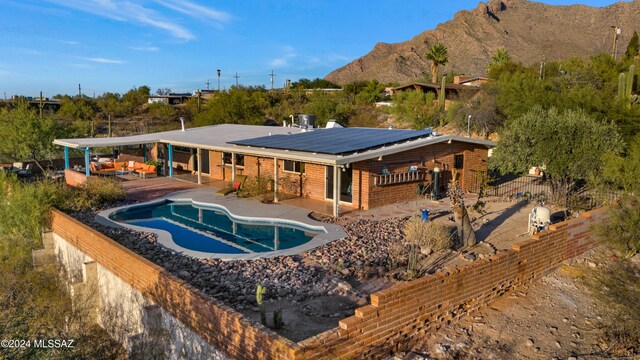 rear view of house with a mountain view, solar panels, and a patio