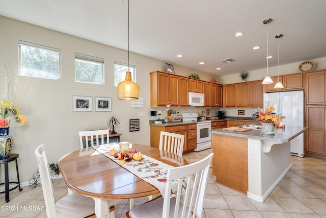 kitchen featuring sink, hanging light fixtures, a kitchen island, white appliances, and light tile patterned flooring