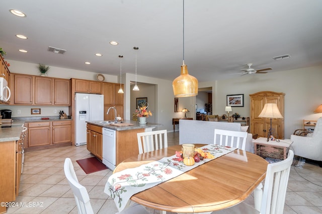 kitchen with sink, decorative light fixtures, white appliances, a center island with sink, and light tile patterned floors