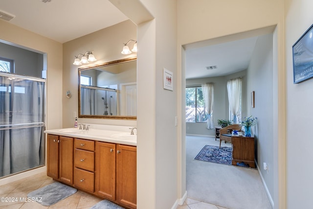 bathroom with tile patterned floors, a shower with door, and vanity