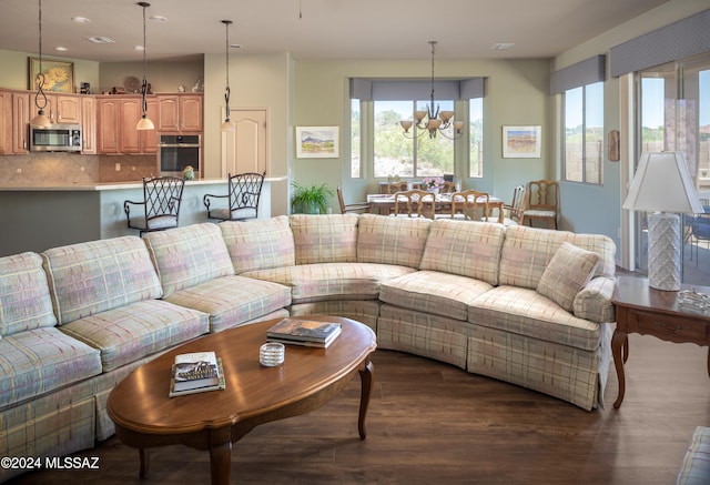 living room with dark hardwood / wood-style floors and an inviting chandelier