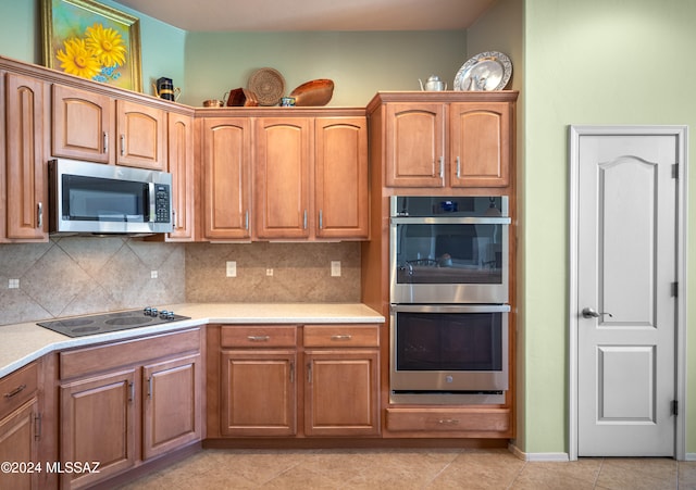 kitchen with backsplash, light tile patterned floors, and stainless steel appliances