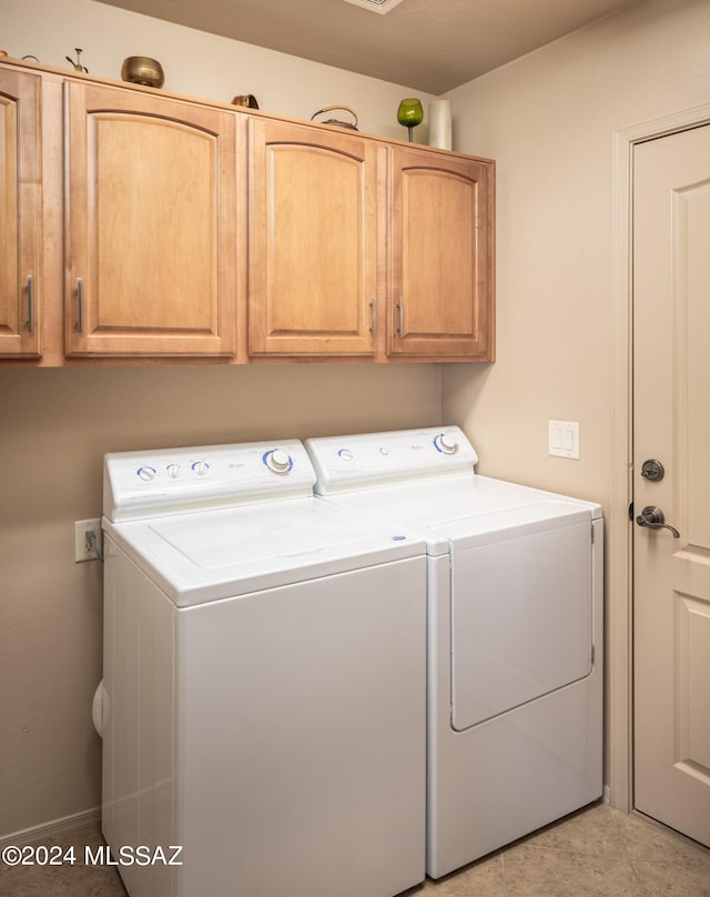 laundry room featuring light tile patterned flooring, cabinets, and separate washer and dryer