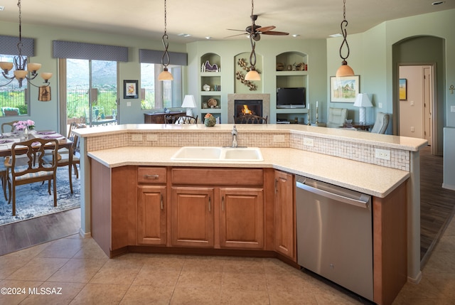 kitchen with built in features, light hardwood / wood-style flooring, stainless steel dishwasher, decorative light fixtures, and a kitchen island with sink