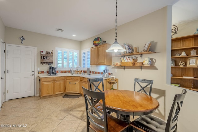 kitchen with pendant lighting, light tile patterned floors, sink, and light brown cabinetry