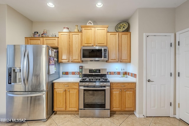 kitchen with light brown cabinetry, light tile patterned floors, and appliances with stainless steel finishes