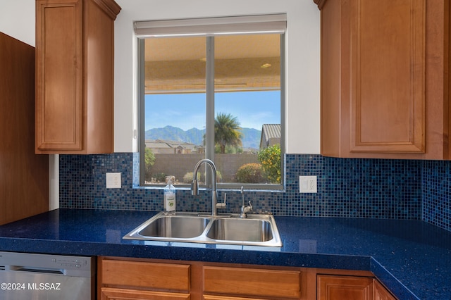 kitchen with a mountain view, decorative backsplash, stainless steel dishwasher, and sink