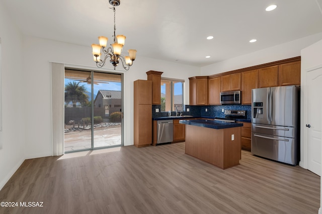 kitchen with an inviting chandelier, hanging light fixtures, a kitchen island, light hardwood / wood-style floors, and stainless steel appliances