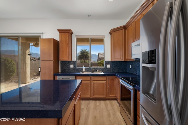 kitchen with tasteful backsplash, sink, stainless steel appliances, and light wood-type flooring