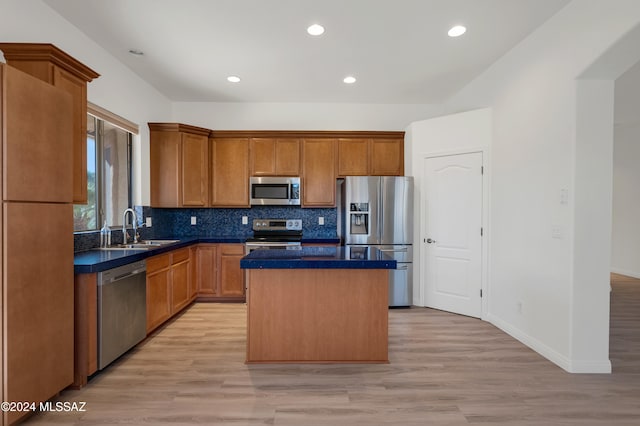 kitchen with sink, backsplash, light hardwood / wood-style floors, a kitchen island, and appliances with stainless steel finishes