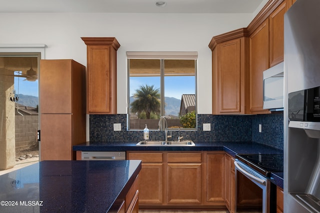 kitchen with sink, backsplash, dark stone countertops, a mountain view, and appliances with stainless steel finishes