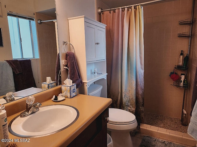 bathroom featuring tile patterned flooring, toilet, vanity, and walk in shower