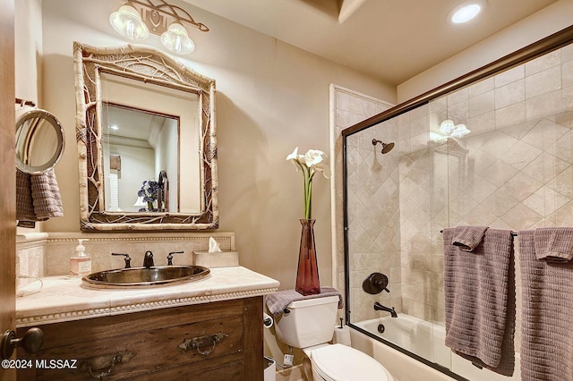 full bathroom featuring vanity, combined bath / shower with glass door, and toilet