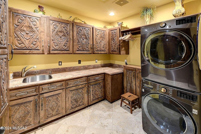 clothes washing area with stacked washer and dryer, sink, and cabinets