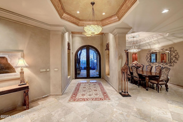 foyer entrance with a tray ceiling, crown molding, french doors, and ornate columns