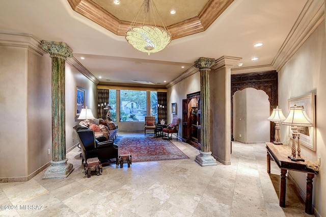 interior space with crown molding, a raised ceiling, and ornate columns