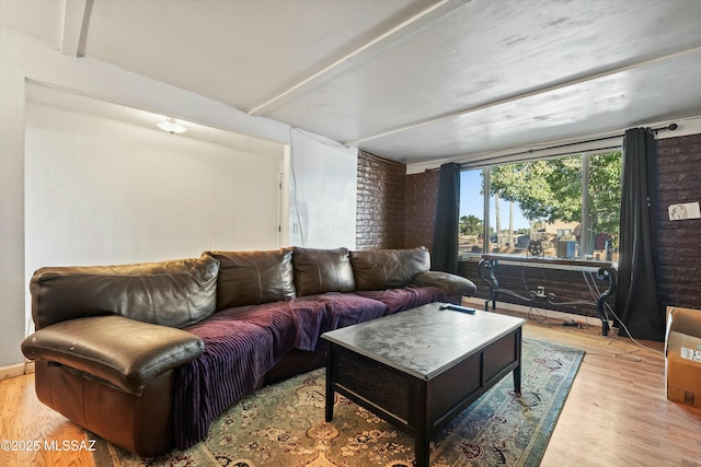 living room with light hardwood / wood-style floors and brick wall